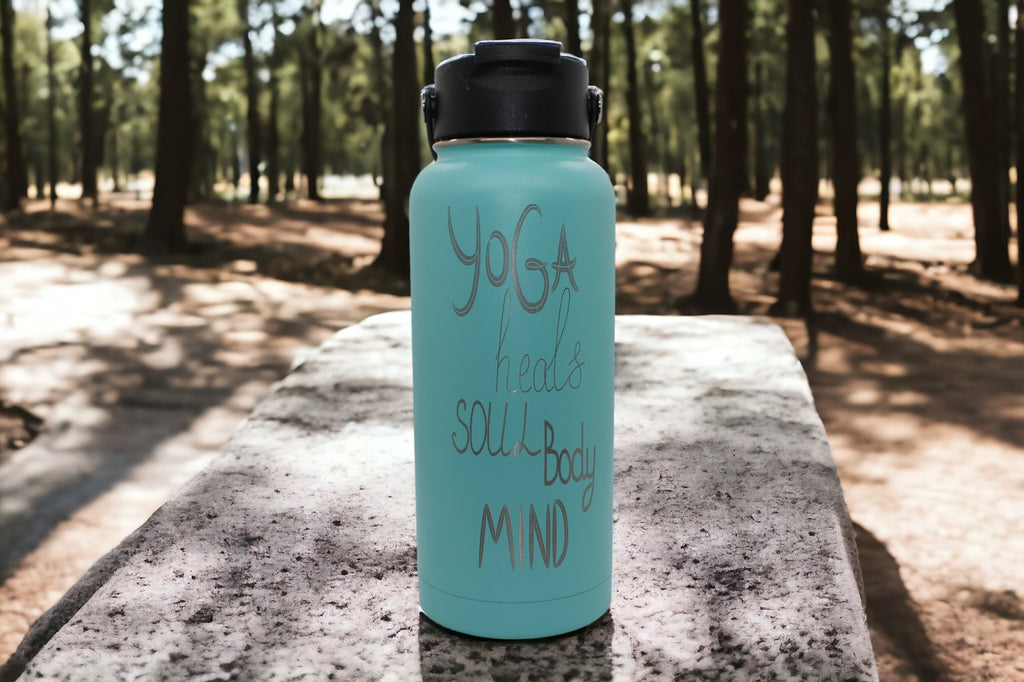 "Image of a teal-colored 32 oz. RTIC water bottle featuring a laser-engraved inscription that reads 'Yoga Heals Soul Body Mind' The personalized aspect allows for customization, making it a unique and thoughtful gift option."